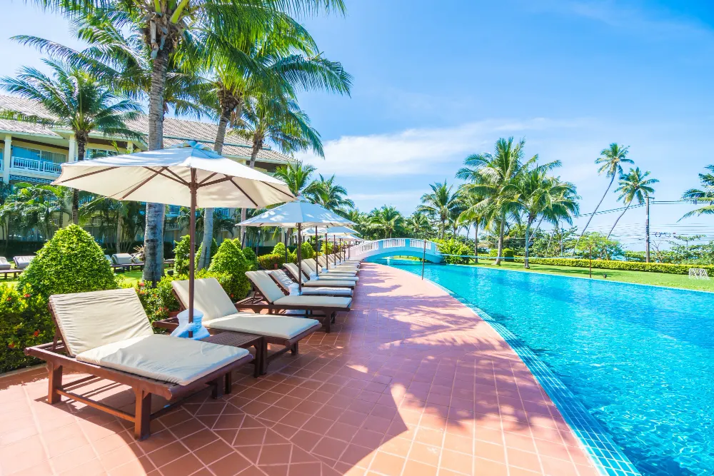 Resort lagoon pool with lounge chairs under palm trees
